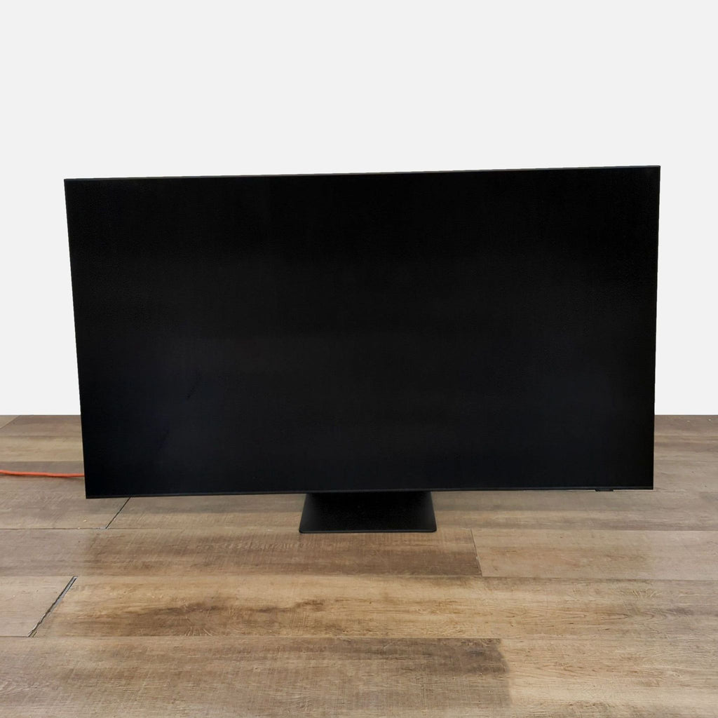 Samsung 65-inch Neo QLED TV on a wooden surface, screen turned off.