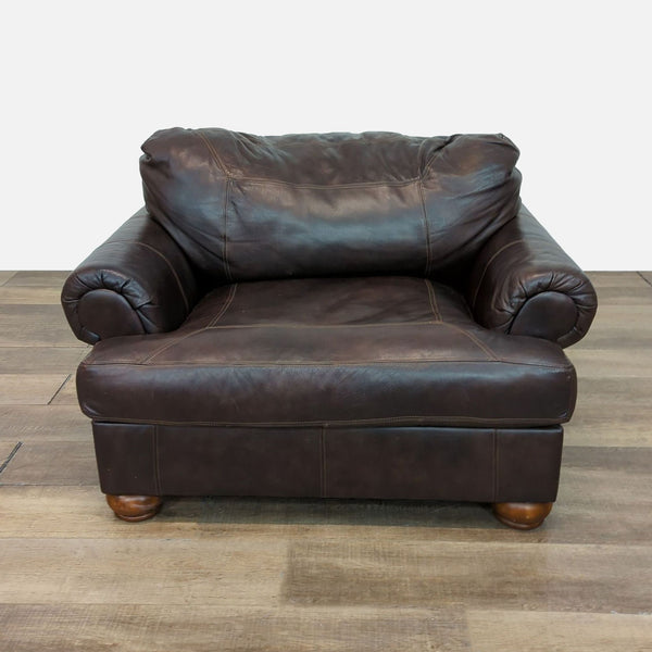 Brown leather club chair with rolled arms and wooden feet, by Ashley Furniture.