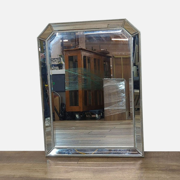 Beveled mirror with ornate mirrored frame reflecting wooden cabinets.