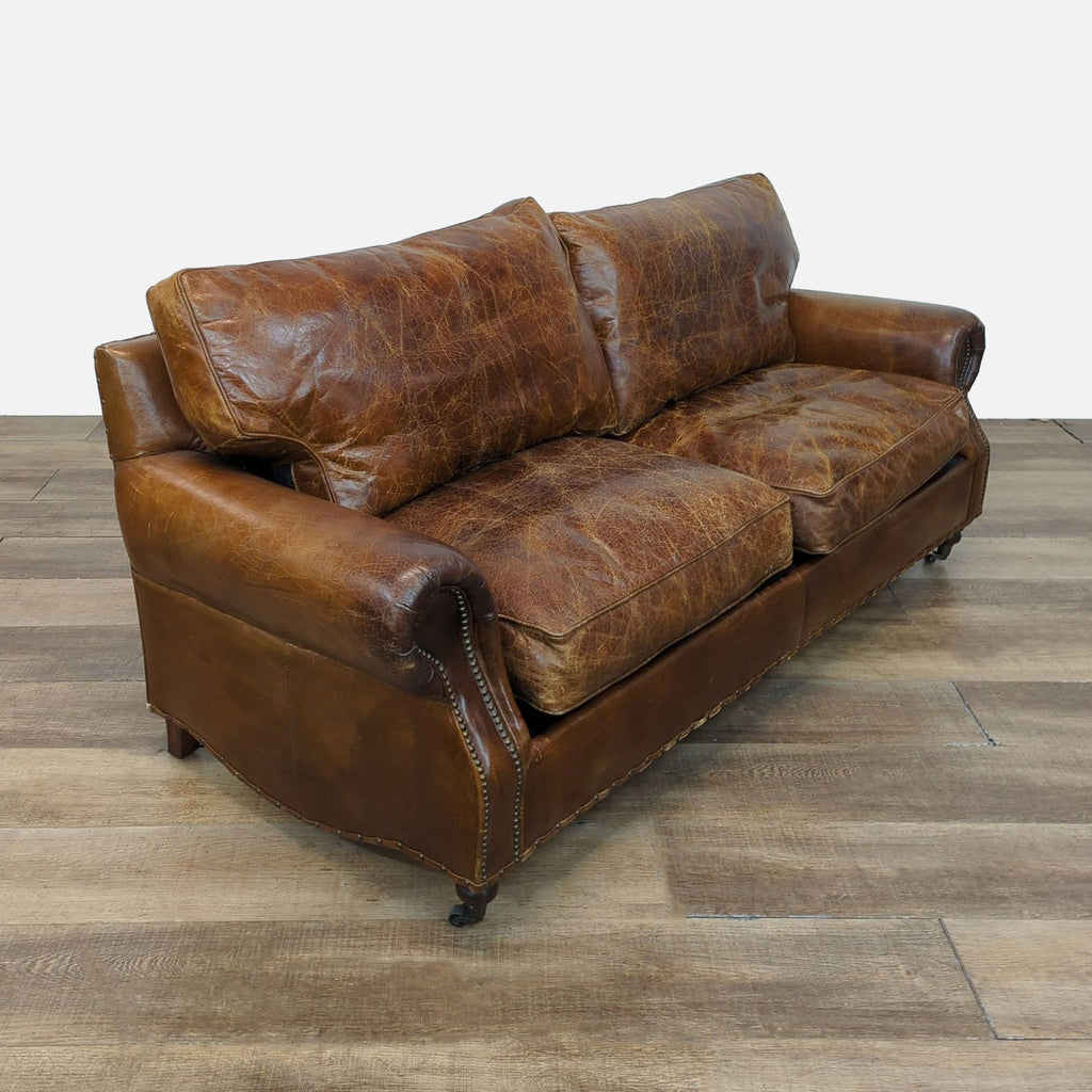 Reperch loveseat featuring distressed leather and turned wood feet with nailhead accents.