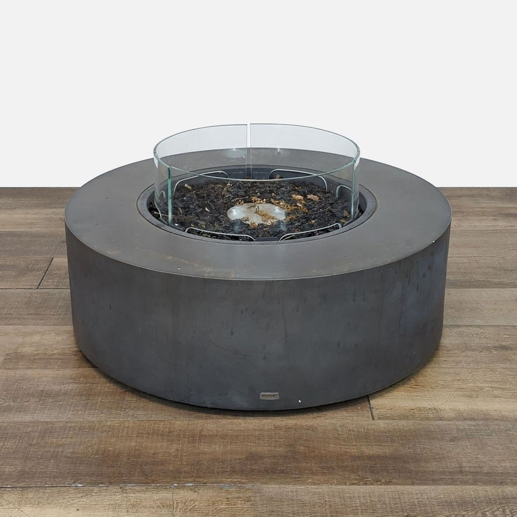 Round EcoSmart fire pit with firescreen on wood floor.