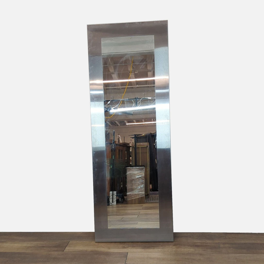 Tall rectangular mirror with sleek metallic frame, standing against a wooden floor.