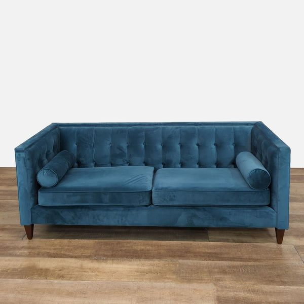 Three-seat blue tufted sofa with removable cushions and tapered wood legs.