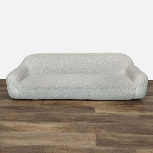 Curved 3-seat sofa with boucle tufted upholstery, displayed on wooden floor.