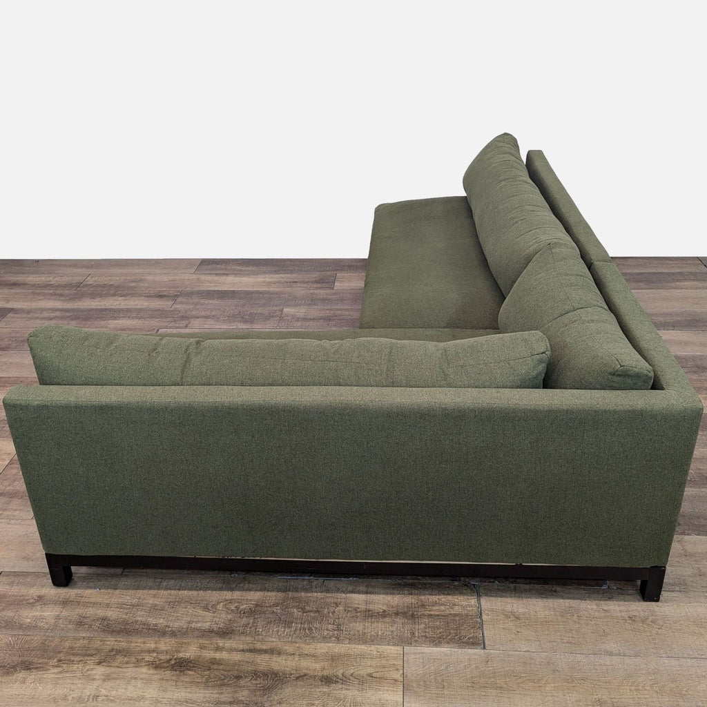 Joybird sectional with green fabric and a sleek wooden bottom frame.