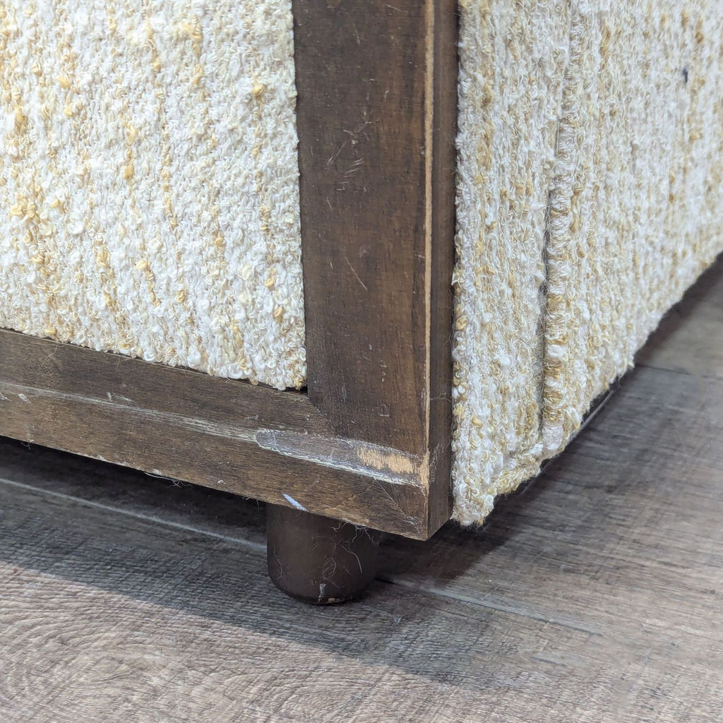 Close-up of wood edging and textured upholstery on vintage loveseat.