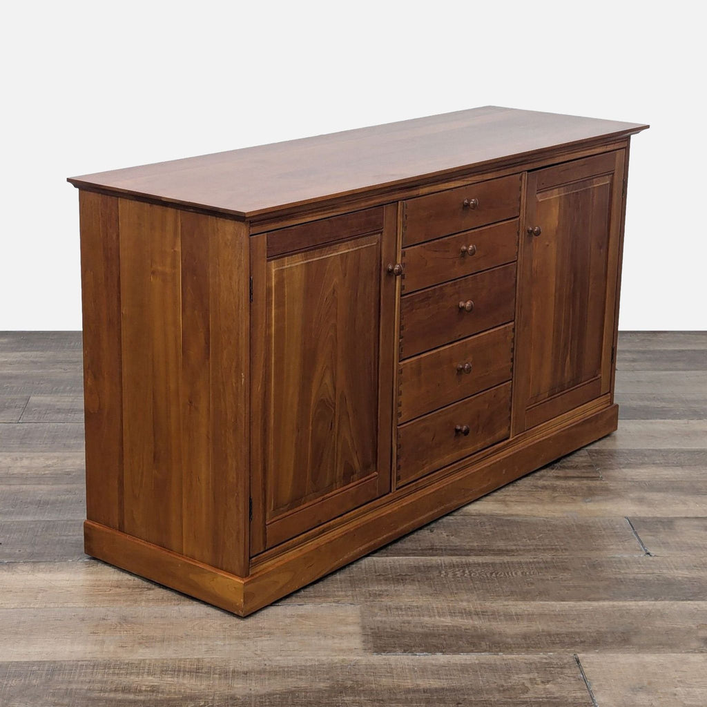 Elegant sideboard with rich wood finish, five drawers, and dual cabinet doors.