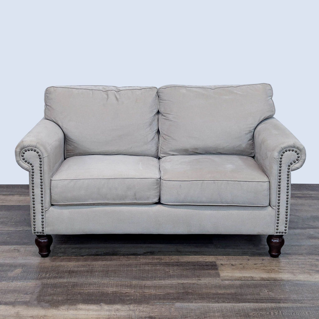 Bauhaus loveseat with rolled arms, nailhead trim, and turned wood feet.