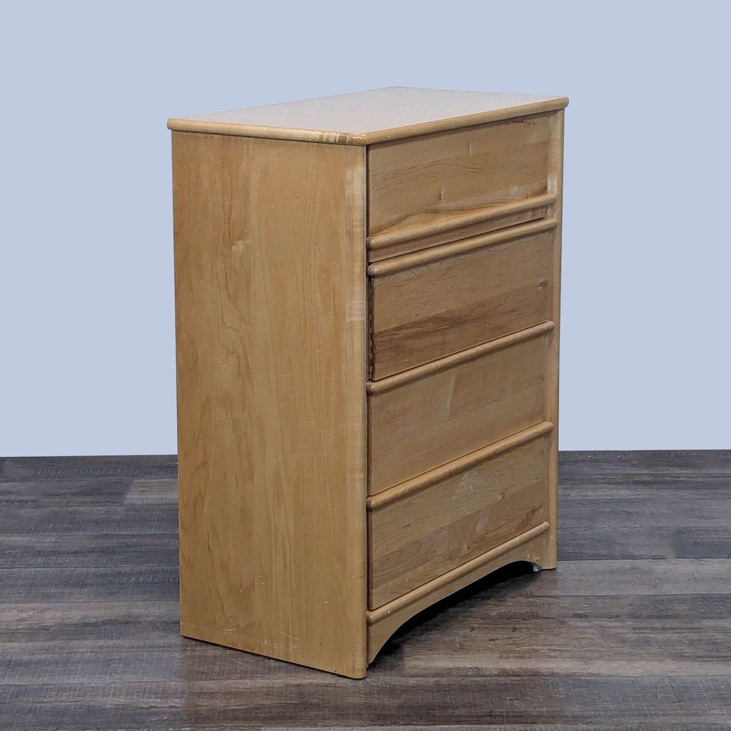 Natural wood dresser from side view, showcasing four closed drawers.