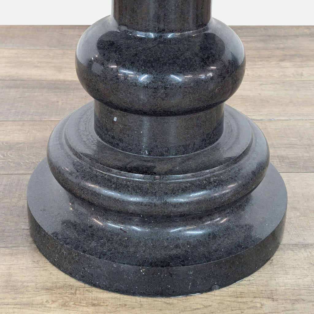 Close-up of black granite pedestal base details on Reperch table.