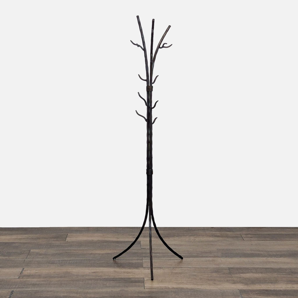 A dark metal coat rack with branch-like hooks on a wooden floor.