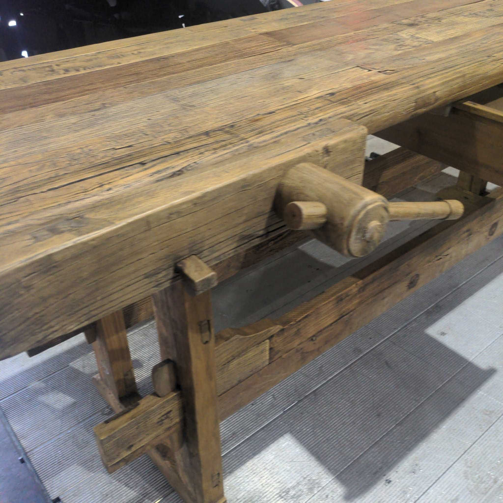 3. Side view of a vintage wood workbench, showing a large manual vise and detailed joinery on the legs.