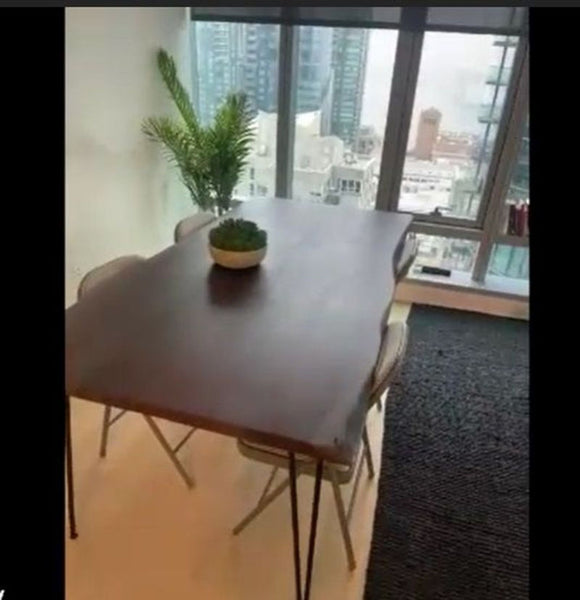 1. Modern dining table with a wooden top and hairpin legs, set in a city-view apartment with plants.