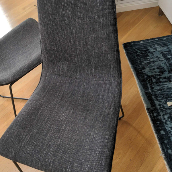 1. Close-up of a gray upholstered West Elm dining chair with a metal frame on a wooden floor.  