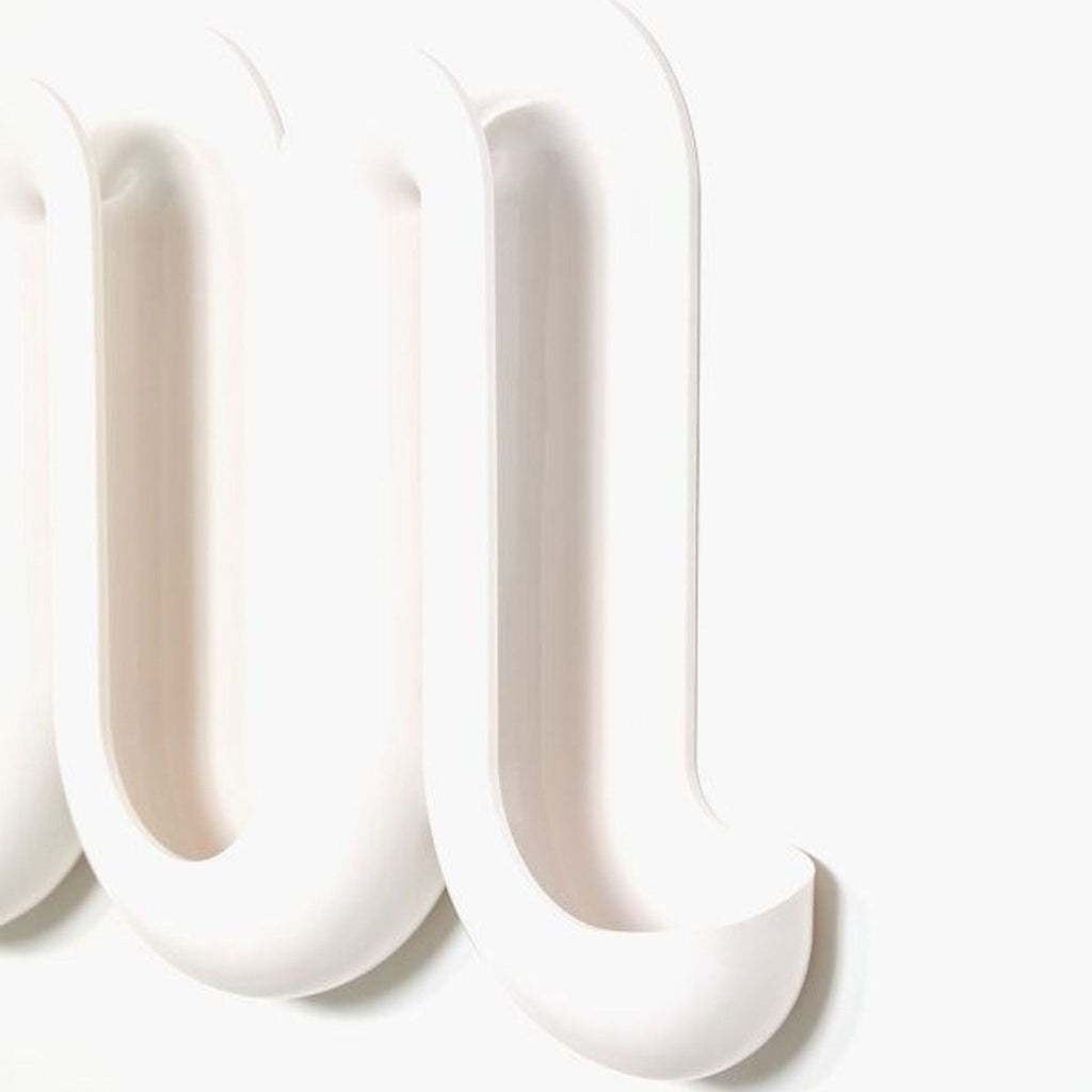 Side view of the Swell Wall Catchall, showcasing its wave-like undulating curves in white plastic.