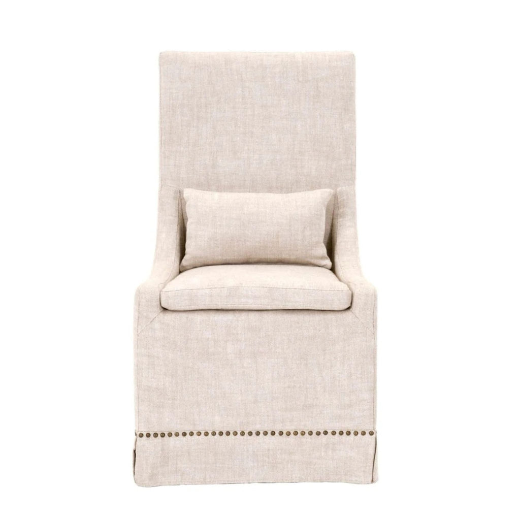 Slipcovered dining chair in bisque French linen with gold nails, features a lumbar pillow.
