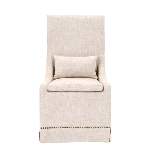 Slipcovered dining chair in bisque French linen with gold nails, features a lumbar pillow.