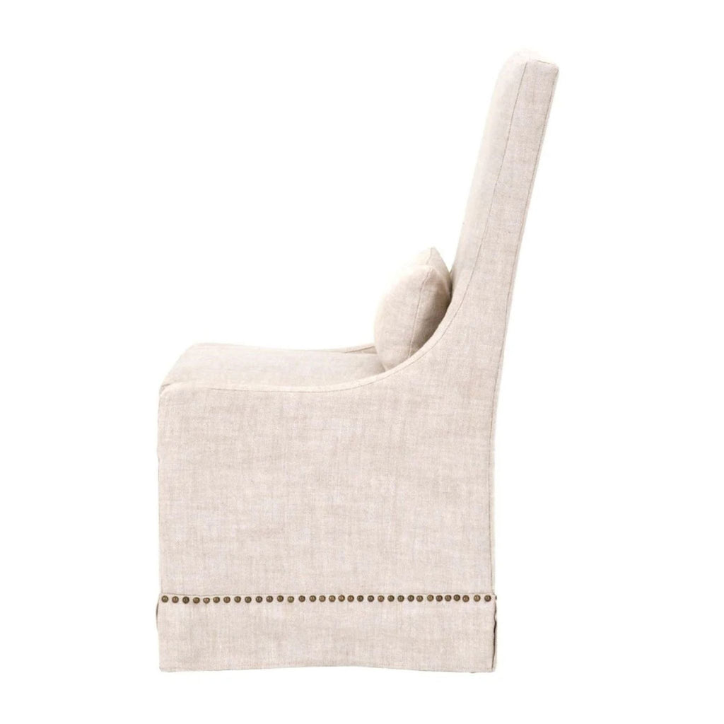 Side view of bisque linen dining chair, adorned with gold nails detailing the base.