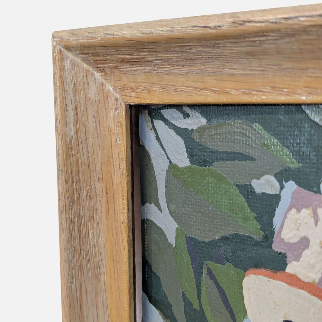 Corner of a wood-framed painting, displaying leaves and soft colors.