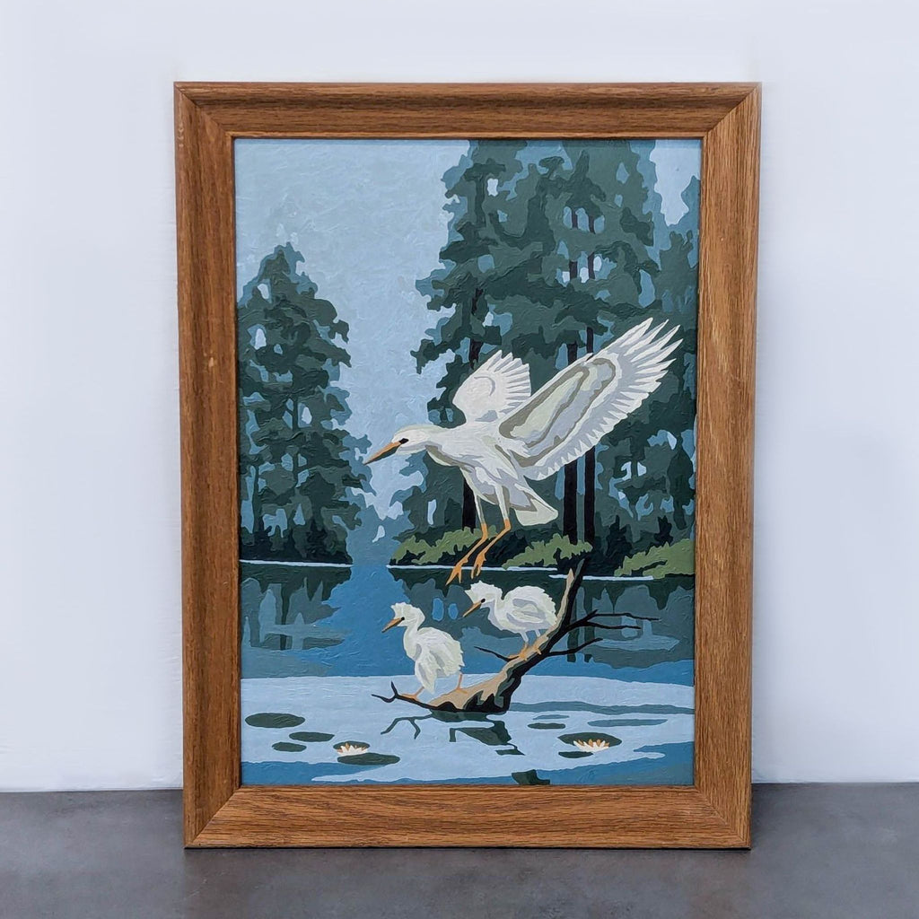 Vintage paint by number of flying heron in wood frame, set against trees and water.
