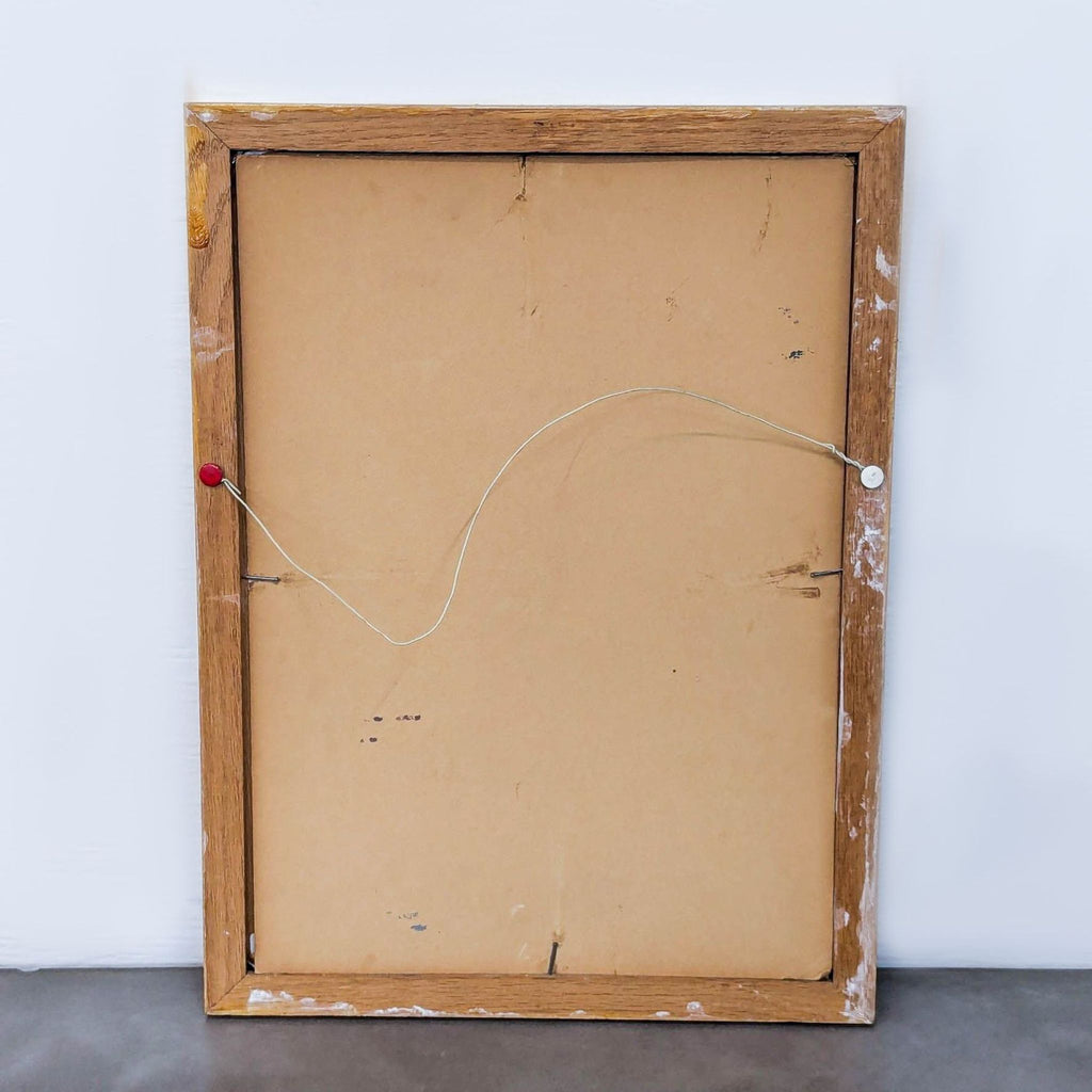 Back view of a vintage wooden-framed painting with hanging wire.