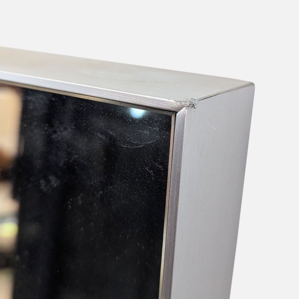 Close-up of a mirror's aluminum frame with a silver finish and a small dent.  