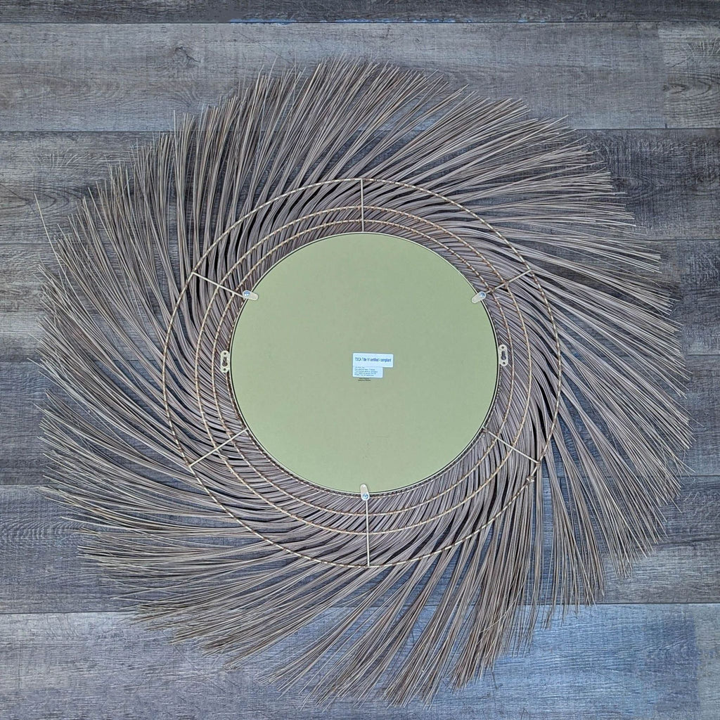 Back view of round mirror with woven coconut fronds and green backing.