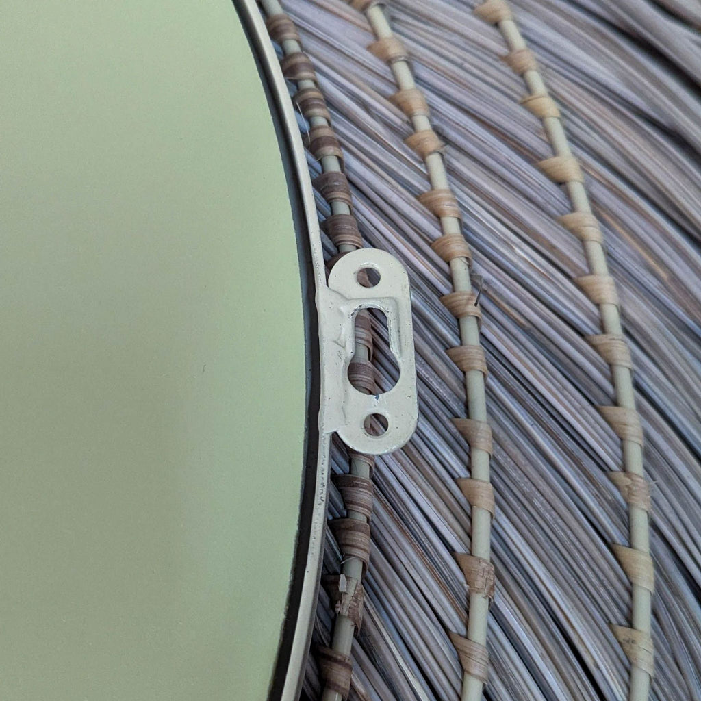 Close-up of mirror's metal hanging bracket and woven frame detail.