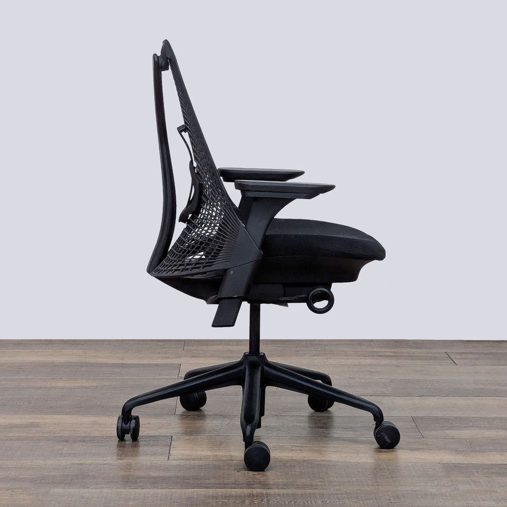 Side view of a Sayl chair displaying its ergonomic mesh back and cushioned seat on wheels.