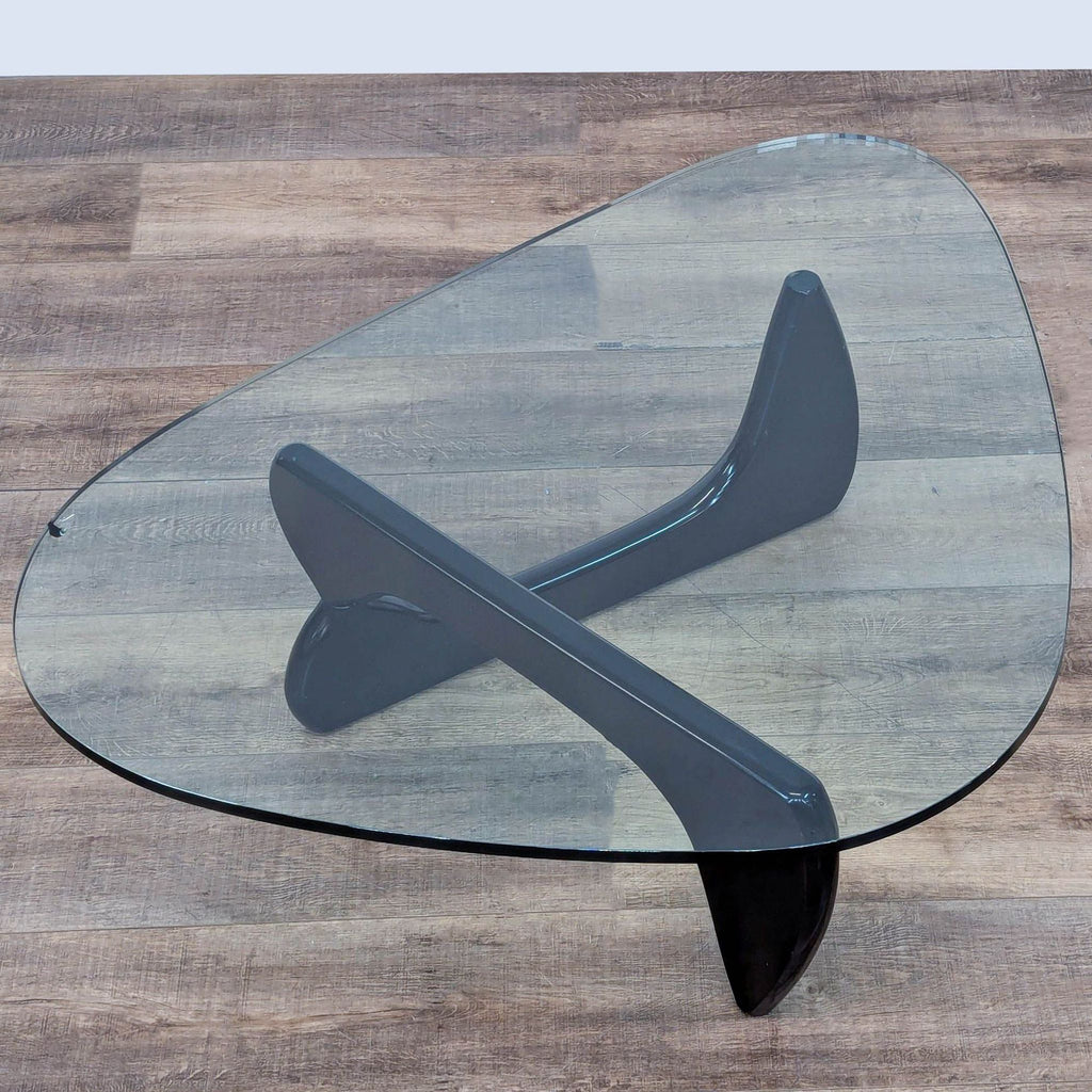 Elegant coffee table with sculptural wooden base and clear glass surface by Herman Miller.