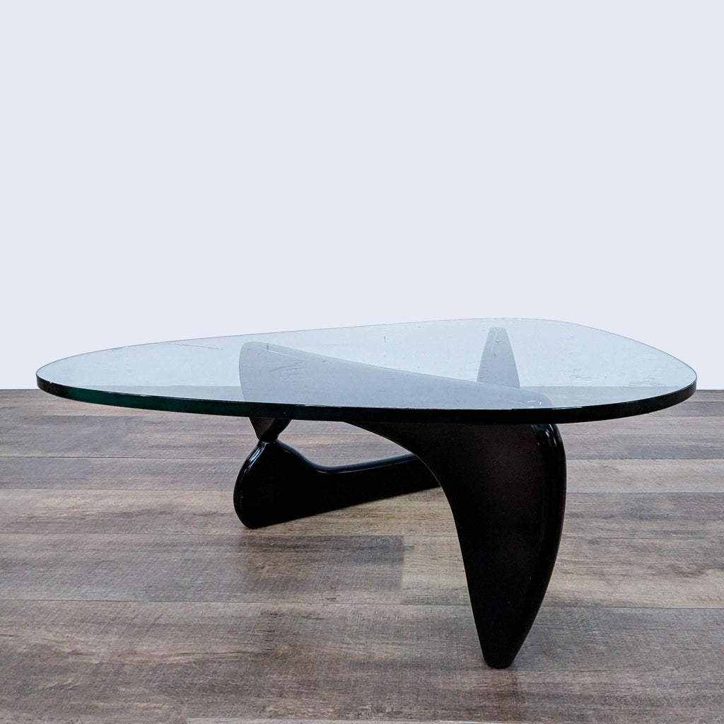 Isamu Noguchi's table featuring a thick glass top and unique interlocking wooden base.