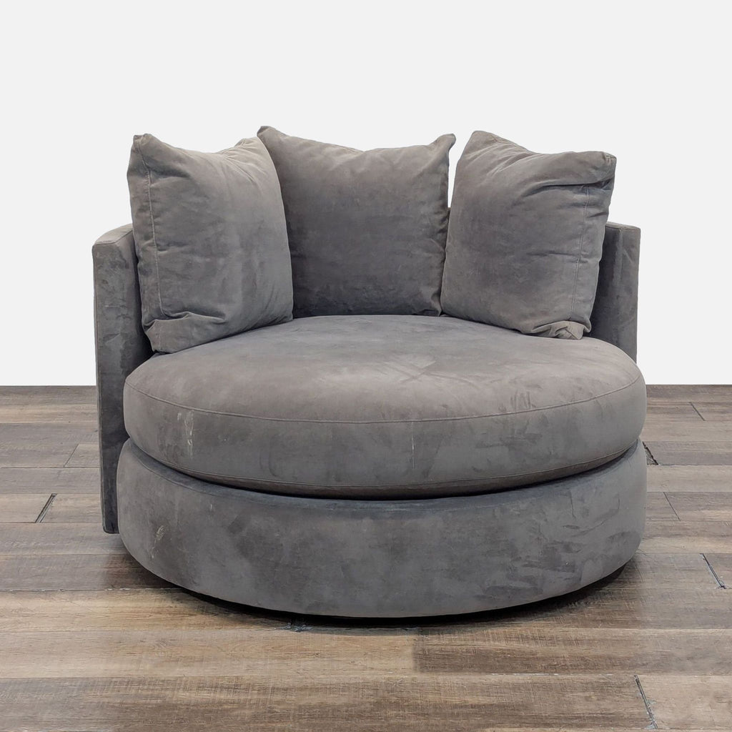 Gray swivel lounge chair with plush pillows, perfect for two. Barrel back design on wooden floor.