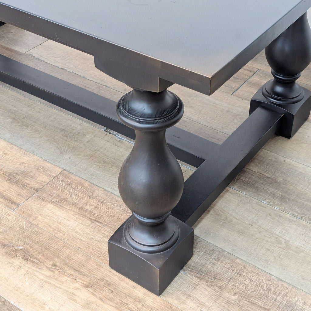 Close-up of the baluster-shaped trestle leg on a Restoration Hardware rectangular wood veneer dining table.