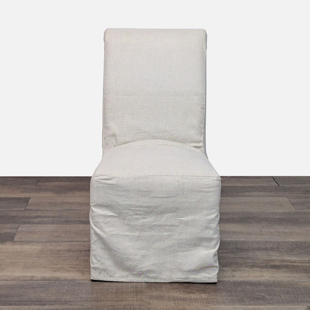 1. Front view of a Pottery Barn Hudson dining chair with a light slipcover, shown on wood flooring.