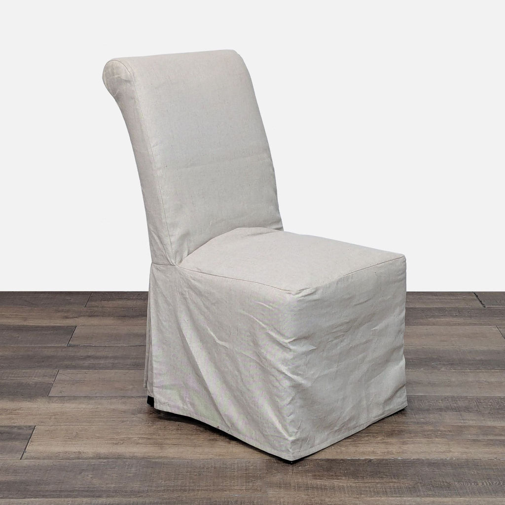 2. Angled side view of a Pottery Barn Hudson slipcovered dining chair, upholstered in light fabric.
