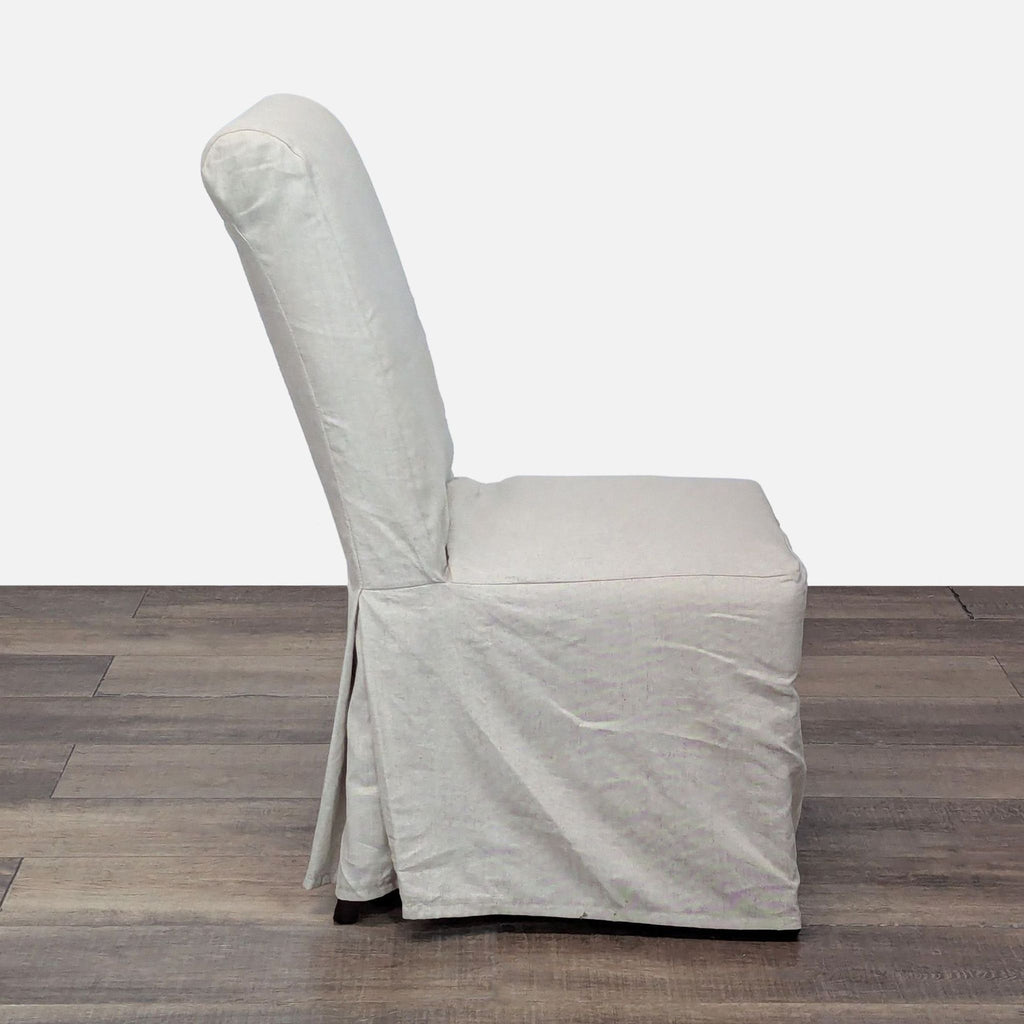 3. Profile view of a Pottery Barn Hudson dining chair with a removable light slipcover and cushioned seat.