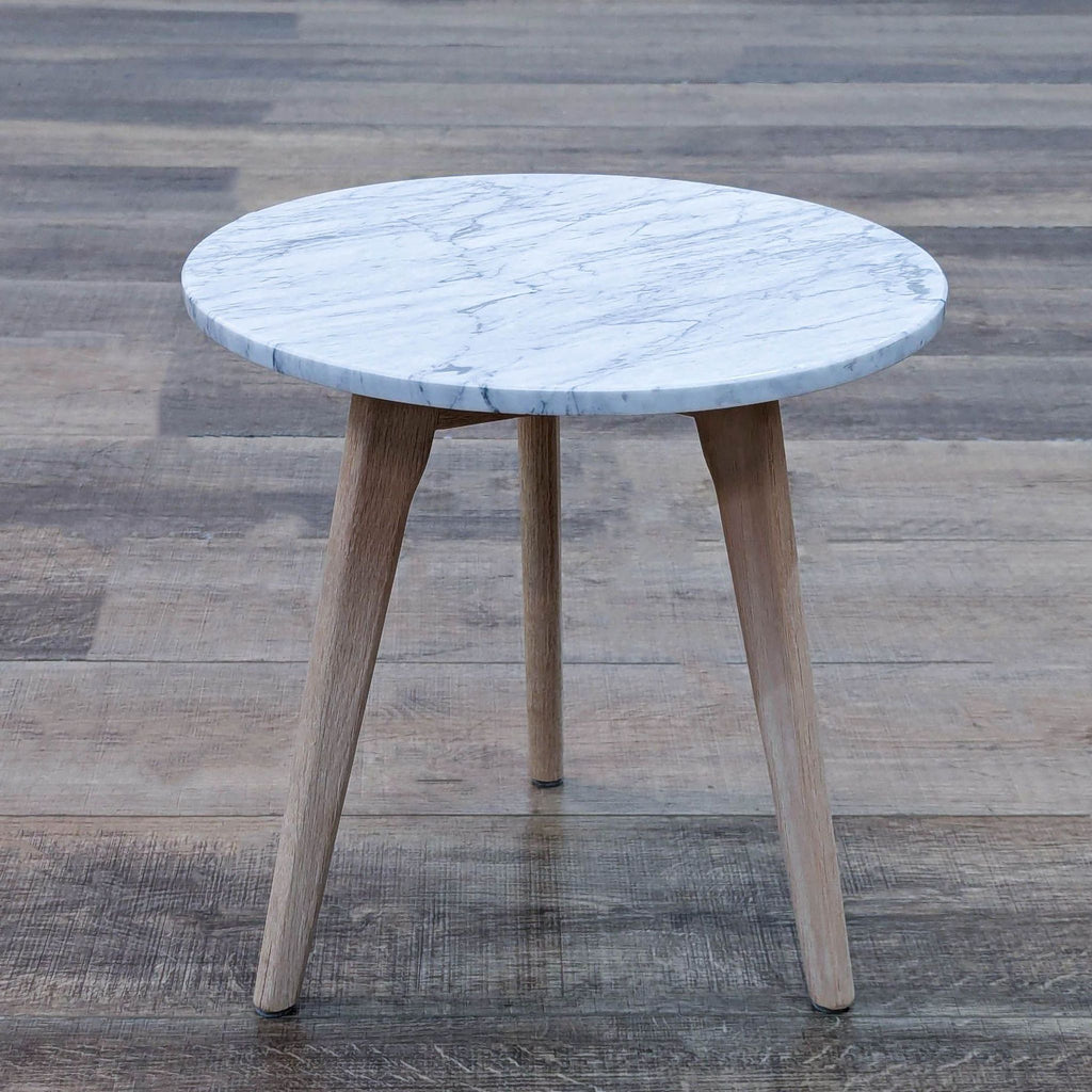 Round table featuring a marble top and engineered wood legs in a Mid-Century design.