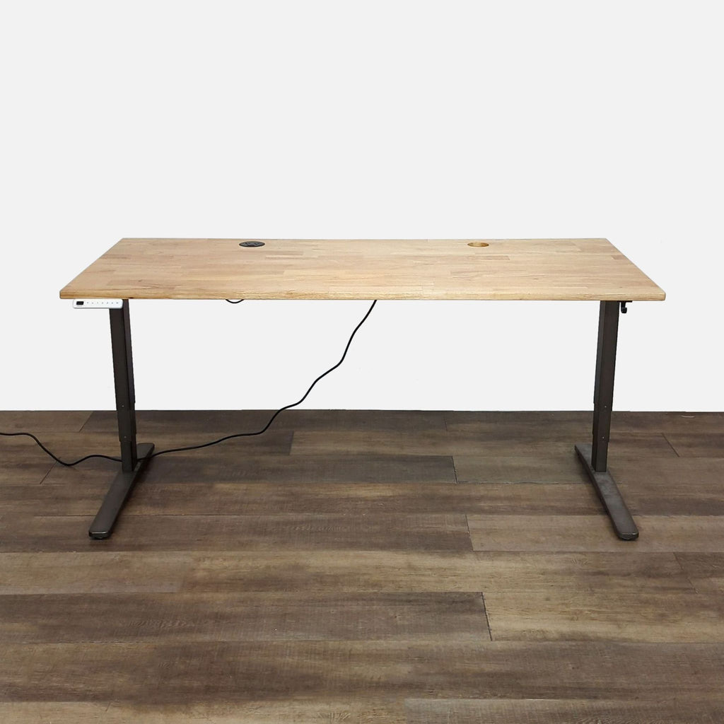 Wooden desktop with power grommet and keypad, part of Uplift Desk.
