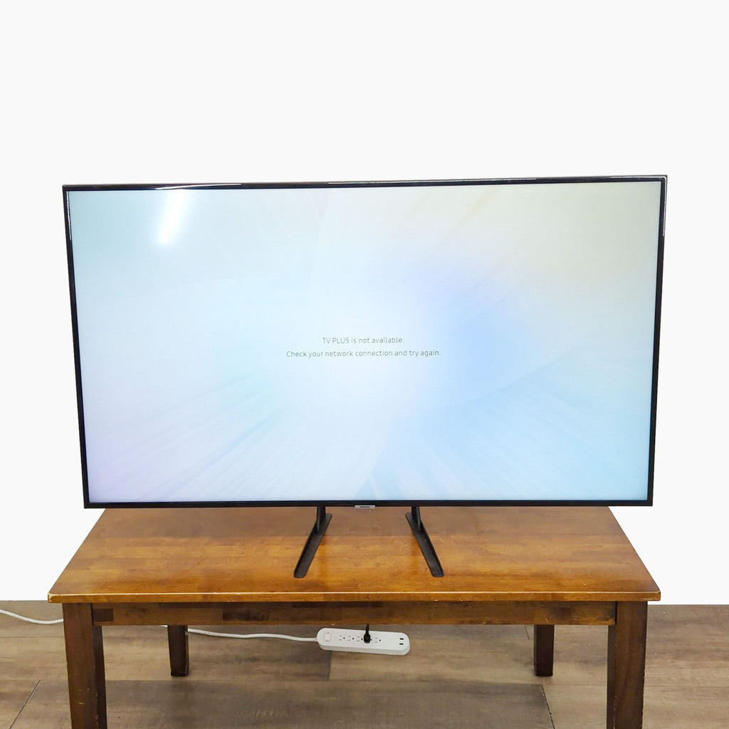 Front view of a Samsung 55-inch 4K UHD TV on a wooden table.