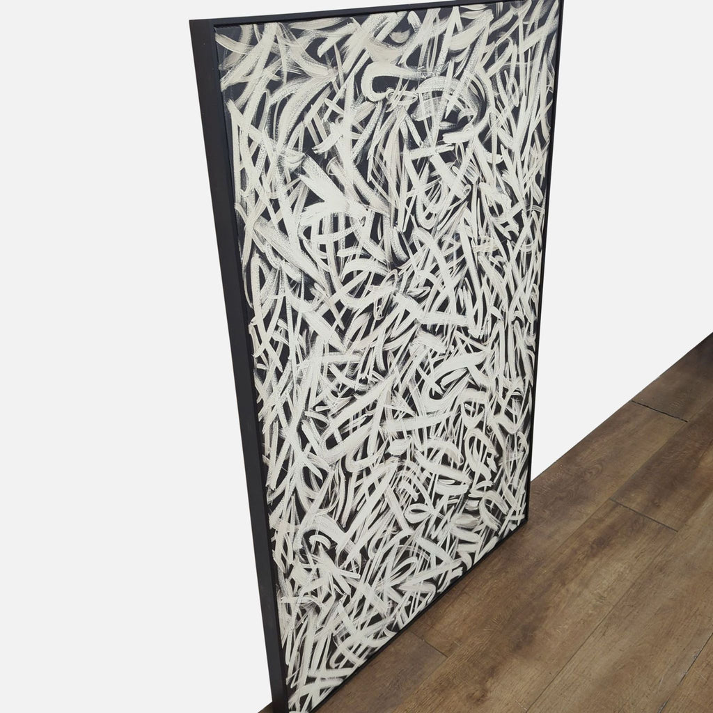 Side angle of black and white abstract canvas artwork in black frame.