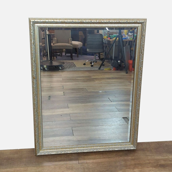Elegant mirror with carved wooden frame, reflecting a room with furniture.