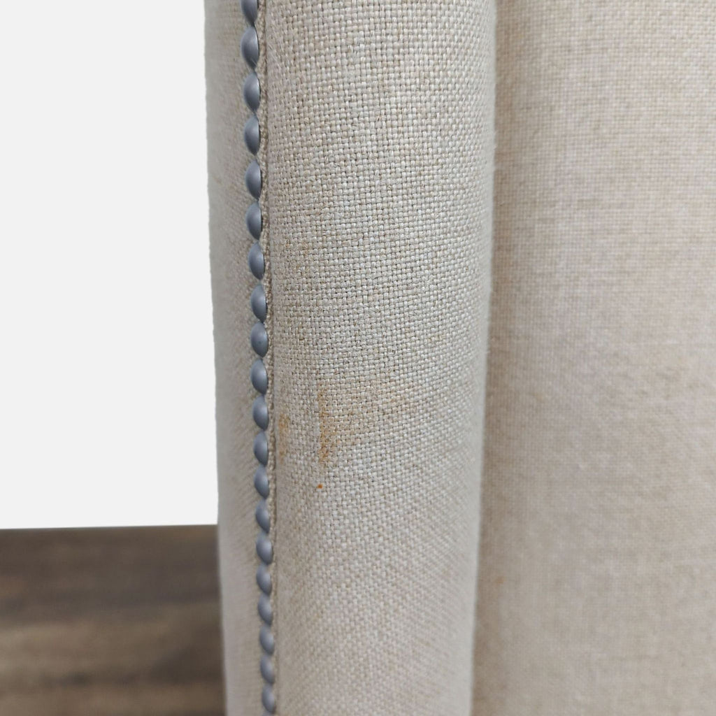 Detailed view of beige fabric with nailhead accents on Reperch dining chair.