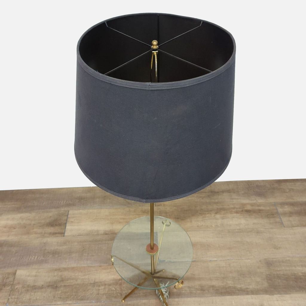 Elegant gold floor lamp with dual-purpose glass table and black shade.