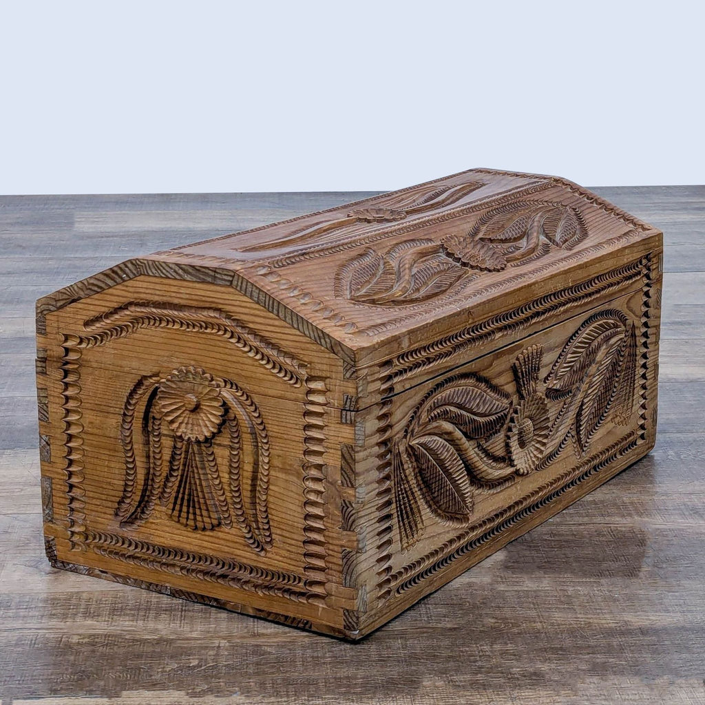 Side view of a carved wooden trunk, displaying ornate floral patterns and rustic design.