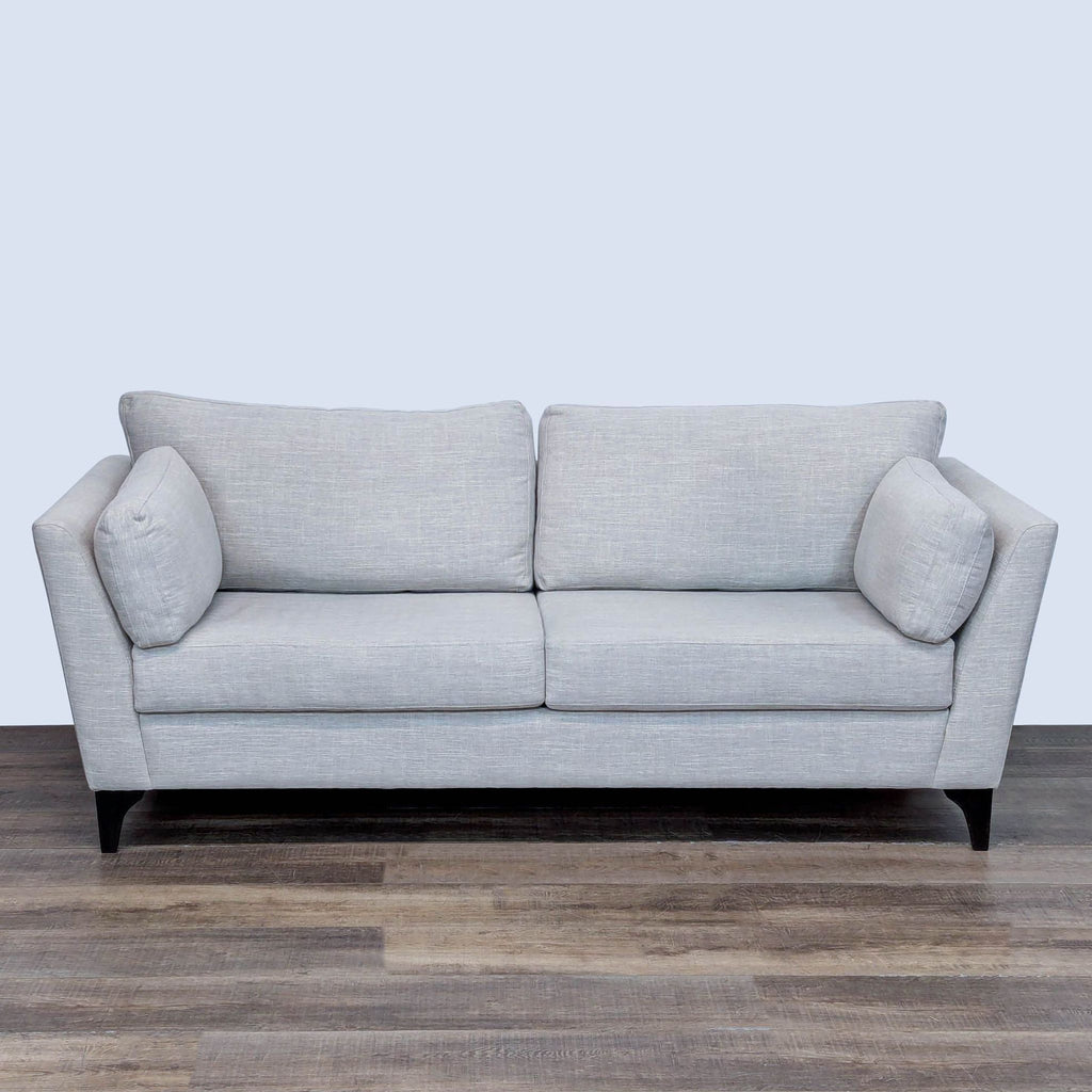 Modern gray loveseat with soft cushions, offering comfort and style.