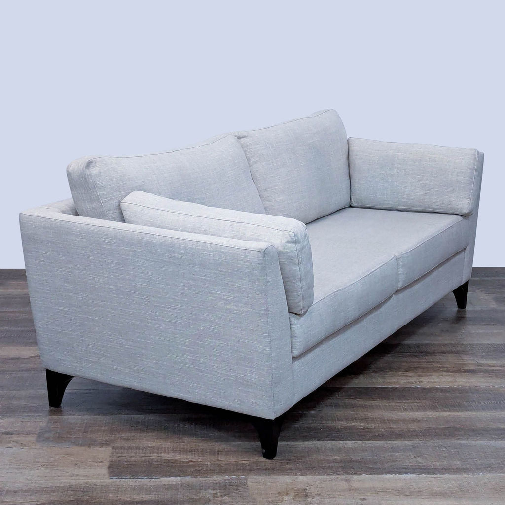Angled view of a gray loveseat, showcasing its stylish form.