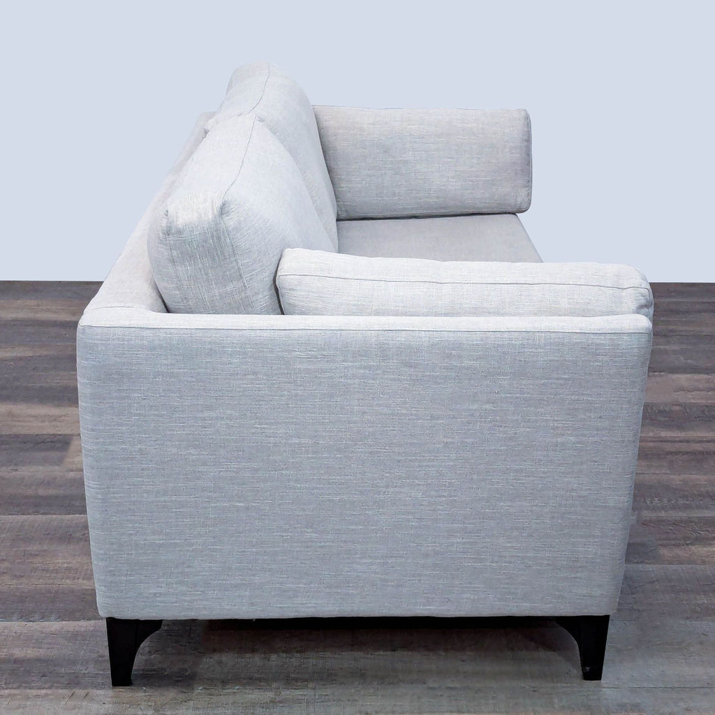 Side view of a sleek gray loveseat with modern design.