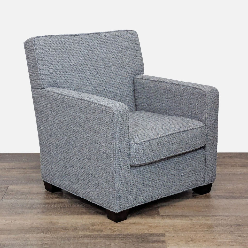 Angled view of a gray lounge chair featuring fabric upholstery and dark wood legs.