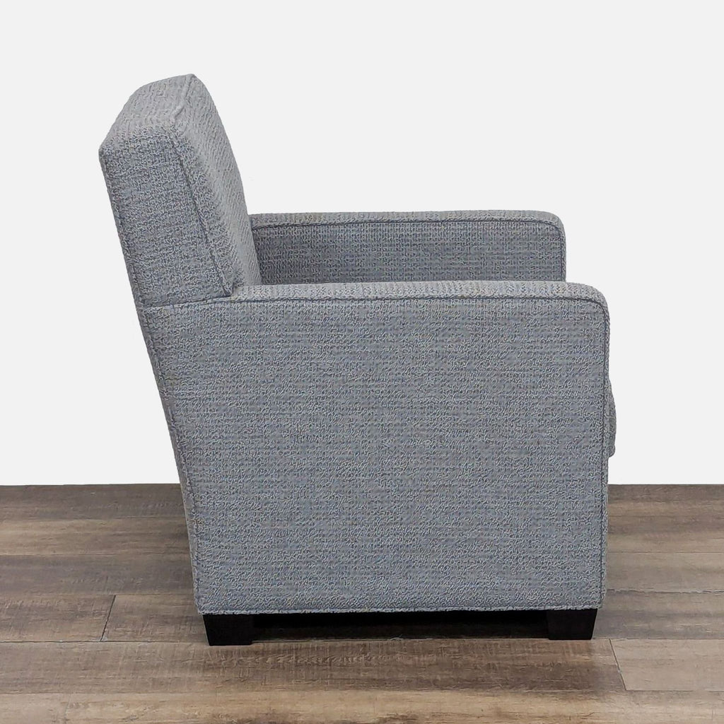Side view of gray lounge chair with fabric upholstery and dark wood feet.
