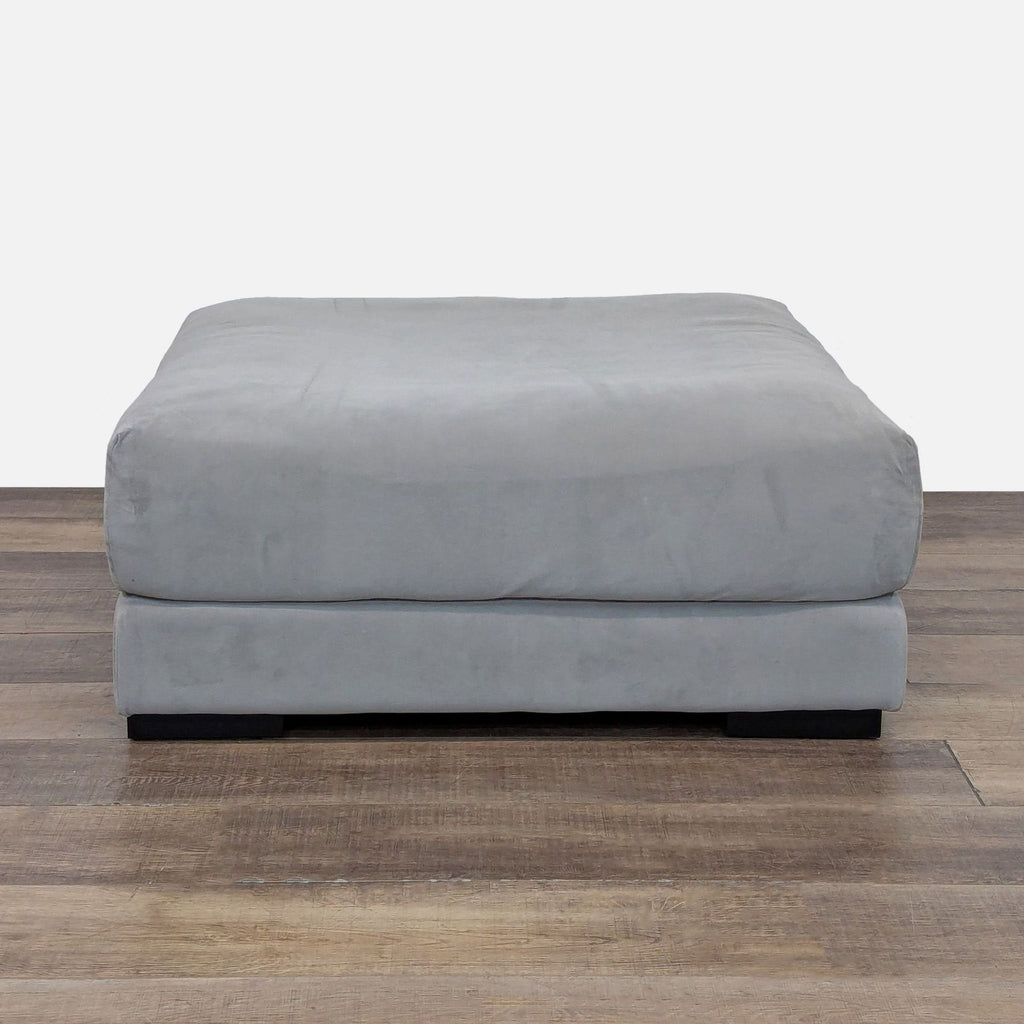 Silver velvet ottoman from West Elm on wooden floor.